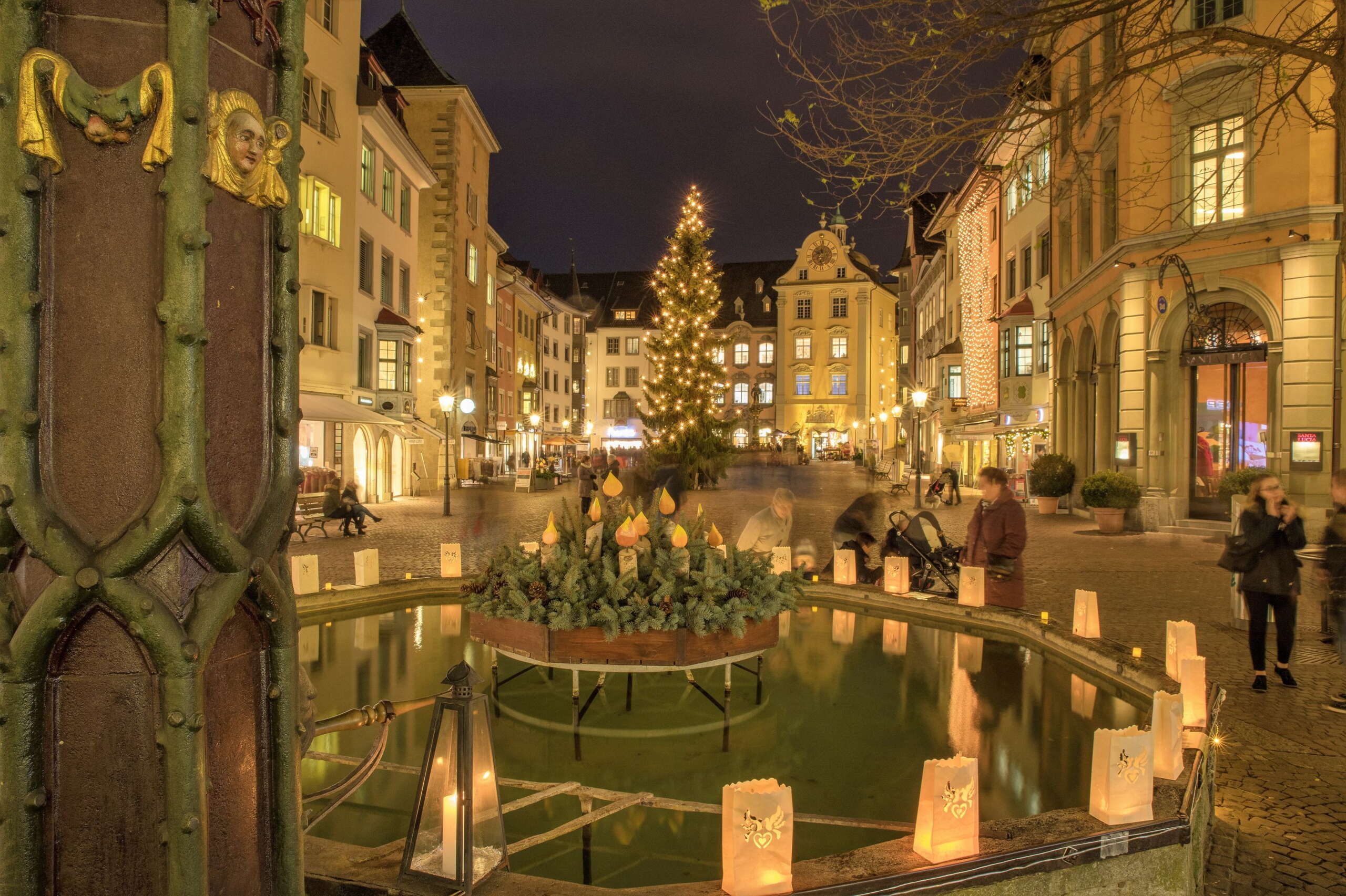 Weihnachtsbeleuchtung auf dem Fronwagplatz in der Schaffhauser Altstadt. In der Mitte steht ein Tannenbaum mit einer Lichterkette und auf dem Mohrenbrunnen stehen Teelichter