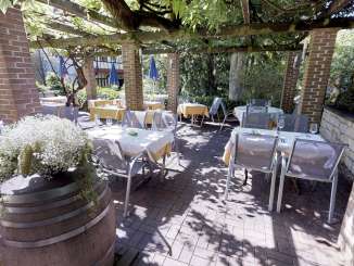 Innenhof Wirtschaft zum Frieden Der Innenhof ist weiss gedeckt. Ein Pavillon mit Grün bedeckt spendet Schatten.
