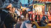Ein Karusell am Weihnachtsmarkt "Märlistadt" in Stein am Rhein. Eine Frau mit Kind im Arm schaut dem Karusell zu.