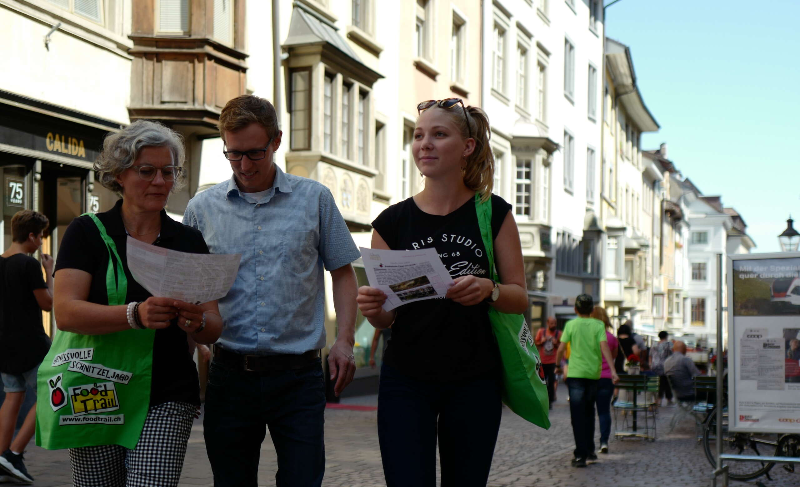 Eine Dreiergruppe die mit einer grünen Jutetasche und dem Quiz in der Hand durch die Schaffhauser Altstadt laufen.