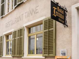 Tanne Schaffhausen Auf einer Hausfassade steht gross "Restaurant Tanne". Es hat grüne Fensterläden und ein eisernes schwarzes Schild mit goldiger Schrift "Hotel Tanne".