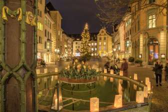 Weihnachtsbeleuchtung auf dem Fronwagplatz in der Schaffhauser Altstadt. In der Mitte steht ein Tannenbaum mit einer Lichterkette und auf dem Mohrenbrunnen stehen Teelichter