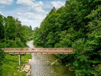 Wutach Schleitheim Brücke Eine Holzbrücke über einem Fluss. Links und Rechts ist ein Wald.