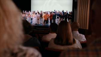 Stadttheater Schaffhausen Aufführung mit Publikum Eine Theaterbühne mit sehr vielen Artisten. Im Saal sitzen Zuschauende auf den roten Sitzen.
