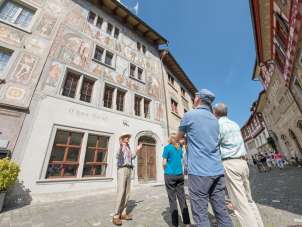 Stadtführung Stein am Rhein Eine Gruppe steht vor einem Haus mit Fassadenmalereien. Ein Guide erzählt mehr darüber.