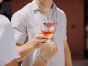 Zwei Personen stossen mit einem Glas Rosé an.