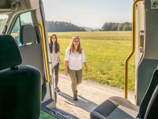 Von innen eines Kleinbus sieht man, wie zwei Personen zum Bus laufen.