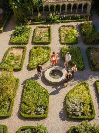 Stadtführung Schaffhausen Eine Gruppe steht um einen kleinen Brunnen im Kräutergarten Schaffhausen. Eine Frau erzählt mehr über die Geschichte.