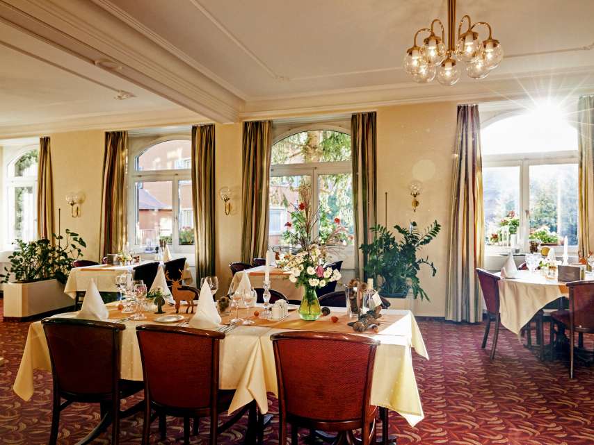 Restaurant Promenade Esssaal mit rotem Teppich, festlich gedeckten Tischen und roten Stühlen.
