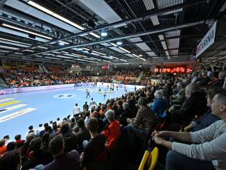 Ein Handballspielfeld mit gefüllten Zuschauerrängen. Das Spielfeld ist blau. Auf einem Banner ist der Schriftzug "BBC Arena" zu lesen.