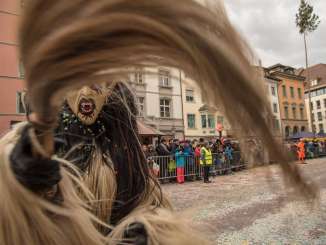 Ein Fasnachtsumzug. Eine verkleidete Hexe ist im Fokus.