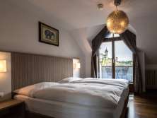 Ein Hotelzimmer ist mit einem Doppelbett mit weisser Bettwäsche ausgestattet. Aus dem Fenster hat man einen Blick auf die Festung Munot in Schaffhausen.auf den Munot.