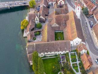 Blick von oben auf das Kloster St. Georgen direkt am Rhein in Stein am Rhein. Man sieht die Kirche mit Kirchenturm, Kreuzgang mit Innenhof und den Garten.