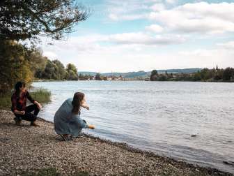 Zwei Freundinnen schiefern Steine am Rheinufer vor Stein am Rhein.
