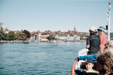 Kursschiff Stein am Rhein An Board des Kursschiffes sind mehrere Personen. Mit Blick voraus sieht man die Schifflände Stein am Rhein.