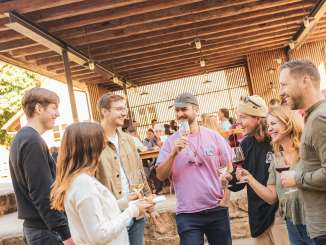 Eine Freundesgruppe steht auf der Strasse zusammen. Alle haben ein Glas Wein in der Hand.