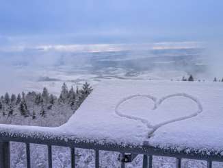 Blick von der Aussichtsplattform des Hagenturms auf eine schneebedeckte Landschaft. Auf einer Tafel liegt Schnee und darin ist ein Herz gezeichnet.
