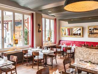 Gedeckte Tische mit weissen Tischtücher und Servietten in einem Restaurant.