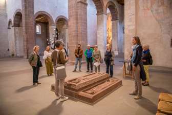 Eine Gruppe mit Guide stehen um Grabplatten in einer Kirche.