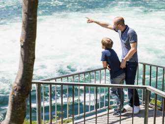 Familie am Rheinfall Ein Vater steht mit seinem Sohn an einem Aussichtspunkt und schauen sich den Rheinfall an.