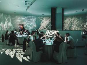 A la Art In einem Raum ist für ein Bankett getischt. Der Raum hat Leinwände an der Decke, Boden und Wänden.