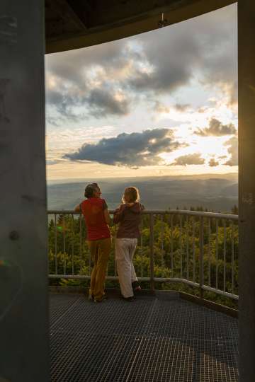 Eine Mutter steht mit ihrer Tochter auf der Aussichtplattform des Hagenturms und geniesst die Abendsonne und die Aussicht.