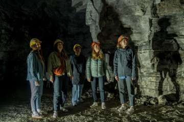 Gipsstollen Schleitheim Fünf Freudinnen tragen gelbe und orange Helme. Sie stehen in einem ehemaligen Gipsstollen.