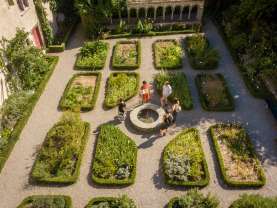 Eine Gruppe steht um einen kleinen Brunnen im Kräutergarten Schaffhausen. Eine Frau erzählt mehr über die Geschichte.