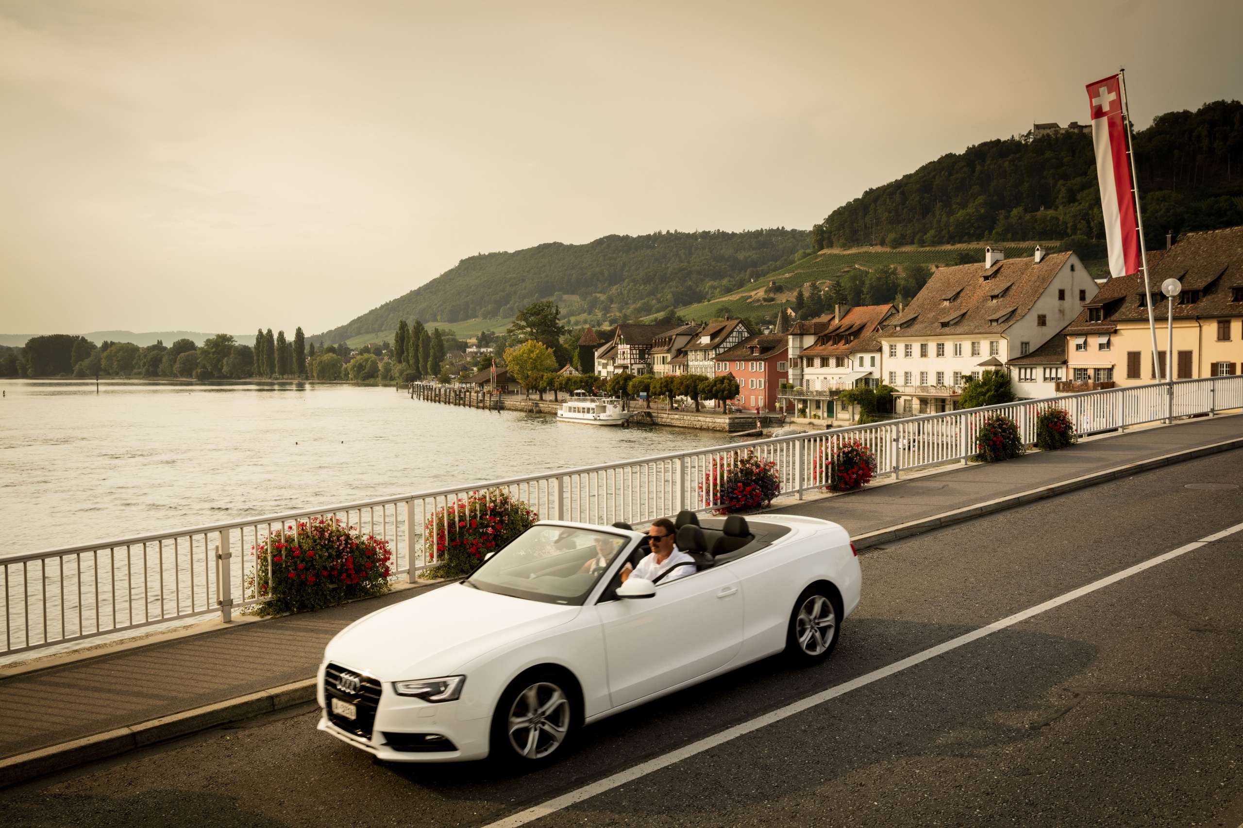 Weisses Cabrio fährt über die Brücke über den Rhein. Im Hintergrund sieht man die Altstadt von Stein am Rhein.