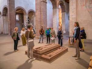Eine Gruppe mit Guide stehen um Grabplatten in einer Kirche.