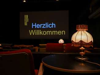 Schaffhauser Filmfestival In einem dunklen Raum stehen diverse rote Sofas und Sessel als Kinostühle. Auf der grossen Leinwand steht "Herzlich Willkommen".