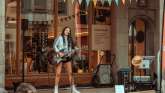 Eine Frau mit Gitarre hat ein Konzert in der Laube vor dem Visitor Centre in der Stadt Schaffhausen.