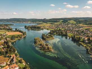 Blick von oben auf den grün-türkisen Untersee mit der Insel Werd. Entlang des Ufers sind kleine _Dörfer und grüne Landschaft.