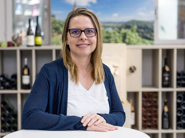 Portrait Sandra Keller. Sie hat blond braune Haare und trägt eine Brille, ein weisses Shirt und ein dunkel blaues Jäckli.