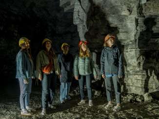 Fünf Freudinnen tragen gelbe und orange Helme. Sie stehen in einem ehemaligen Gipsstollen.