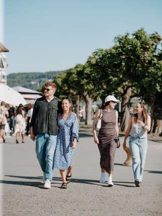 Flanieren Stein am Rhein Vier Personen flanieren entlang der Uferpromenade von Stein am Rhein im Sommer.