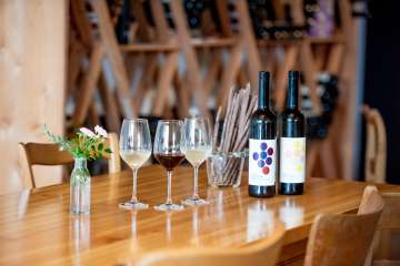 Leibacher Wein Stein am Rhein Auf einem Holztisch stehen Grisini, eine Falsche Rot- und eine Falsche Weisswein sowie zwei Weisswein- und ein Rotweinglas.