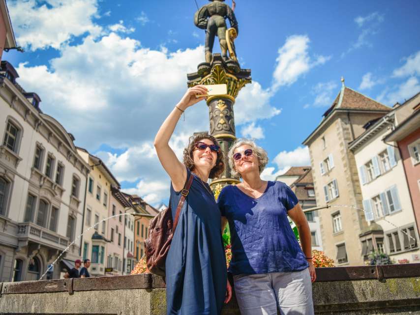 Flâner à Schaffhouse Deux amies se tiennent devant une fontaine de la vieille ville et prennent un selfie.