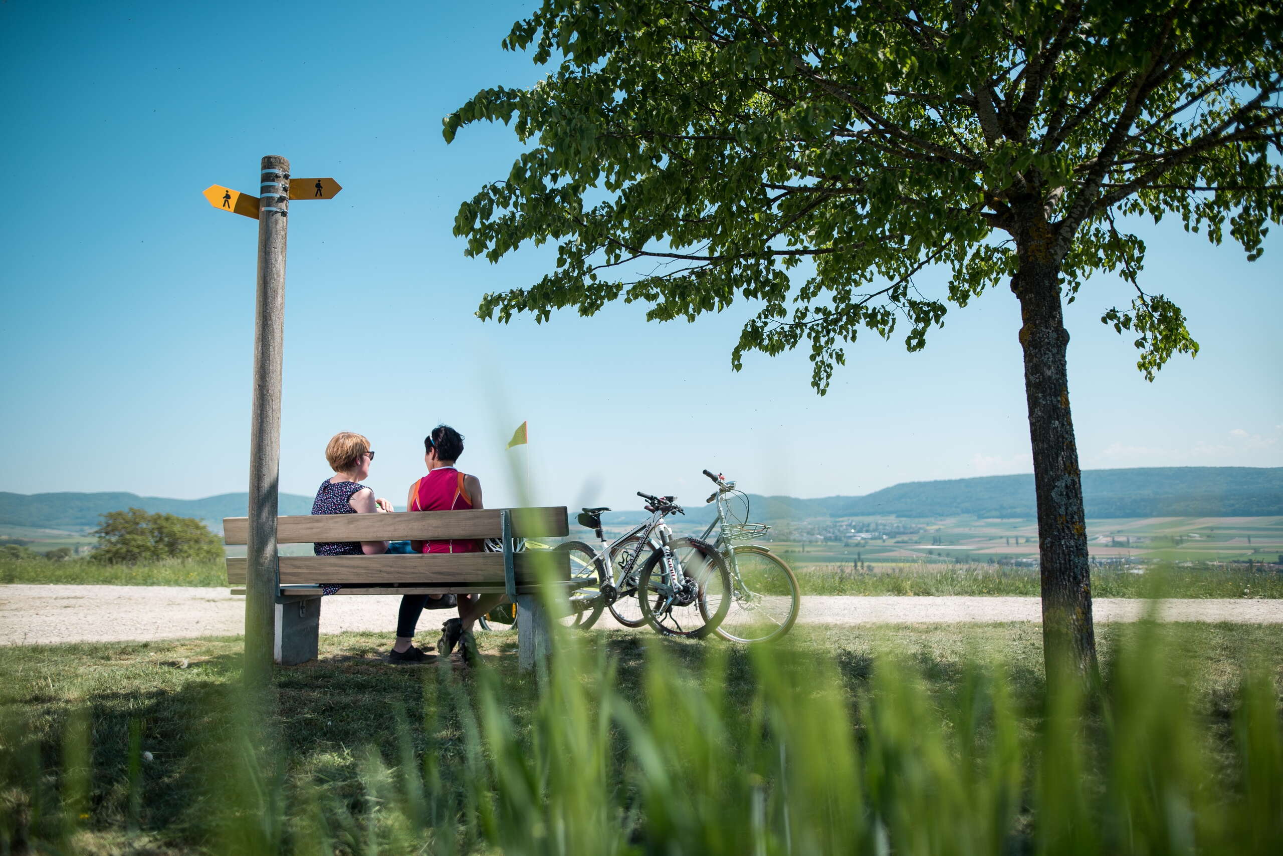 Zwei Frauen, die auf einer Sitzbank eine kurze Pause machen und die Aussicht über das ländliche Klettgau geniessen.