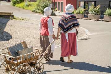Wöschwiiber Führung Wilchingen Zwei Wöschwiiber laufen mit einem Leiterwagen aus Holz durchs Dorf. Sie tragen eine weisse Haube.