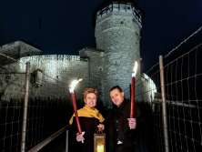 Ein Mann und eine Frau stehen mit je eine brennenden Facker vor der Festung Munot. Sie hält ebenfalls eine Laterne mit Kerze.