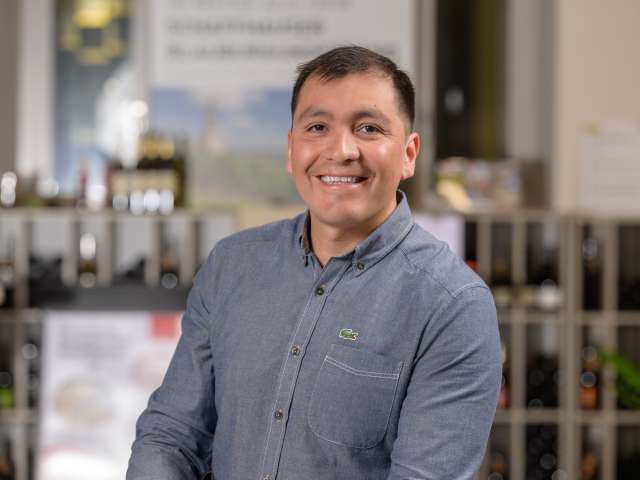 Portrait Paul Mendoza. Er hat schwarze Haare und trägt ein grau blauer Lacoste-Hemd.