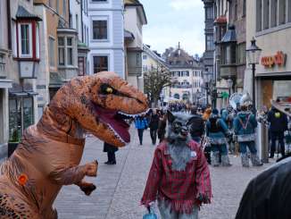 An der Fasnacht. Ein Personen mit einem Dino und Wolfkostüm stehen nebeneinander.