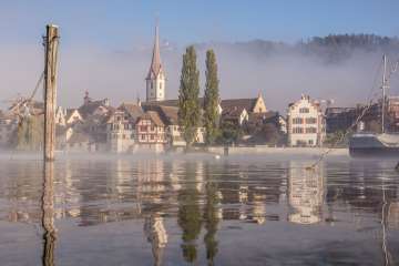 Das Städtchen Stein am Rhein spiegelt sich im Wasser. Über dem Wasser liegt ein leichter Nebel.