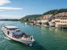 Ein Schiff mit der Aufschrift Arenenberg. Fotografiert von einer Brücke. Im Hintergrund ist eine Altstadt zu sehen.