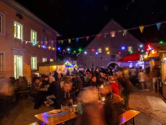 Festbänke in einer Gass in Löhningen, verschiedene Stände und farbige Lichterketten mit vielen Menschen.