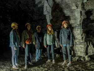 Gipsstollen Schleitheim Fünf Freudinnen tragen gelbe und orange Helme. Sie stehen in einem ehemaligen Gipsstollen.