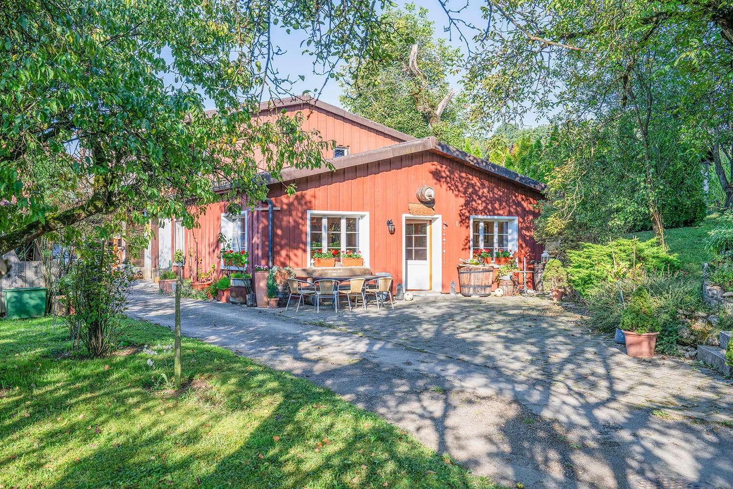 Nägeliseehof Hof mit einer rötlichen Hausfassade umgeben von Grün.