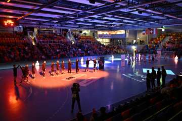 Die Spieler einer Handballmanscht stehen in der Mitte der Halle und klatschen mit dem Gegnerischen Team ab.