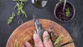 Auf einer Holzplatte sind mehrere Stücke Wildfleisch angerichtet.